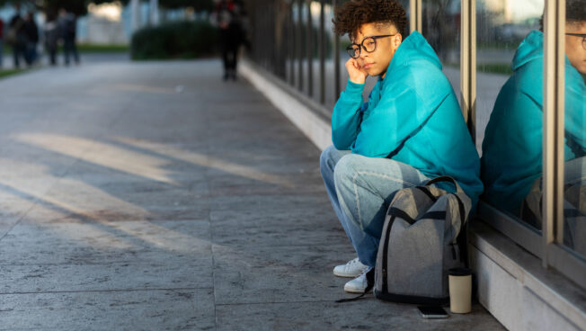 Étudiant malheureux assis avec un sac à dos au lycée